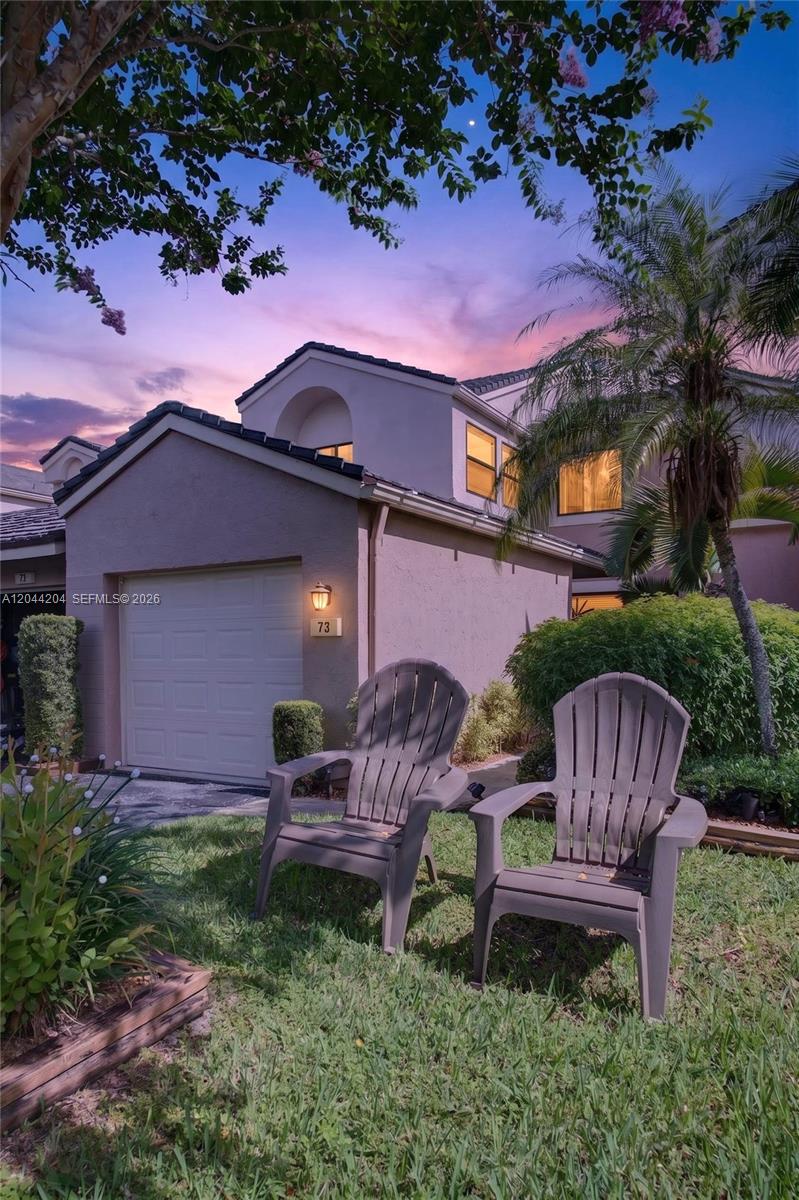 Two plastic Adirondack chairs sit on a lawn in front of a two-story house — 73 NW 98th Ter, Plantation FL 33324, PLANTATION, FL