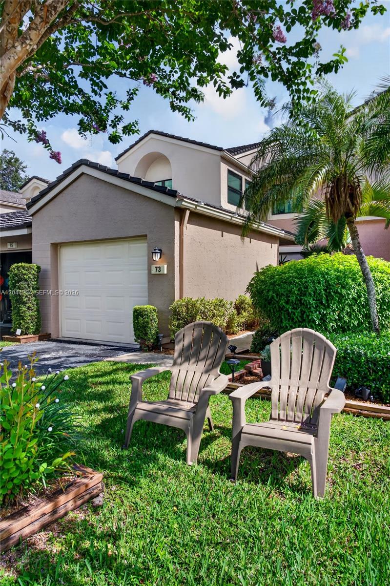 Two plastic chairs sit on a lawn in front of a tan townhouse garage — 73 NW 98th Ter, Plantation FL 33324, PLANTATION, FL