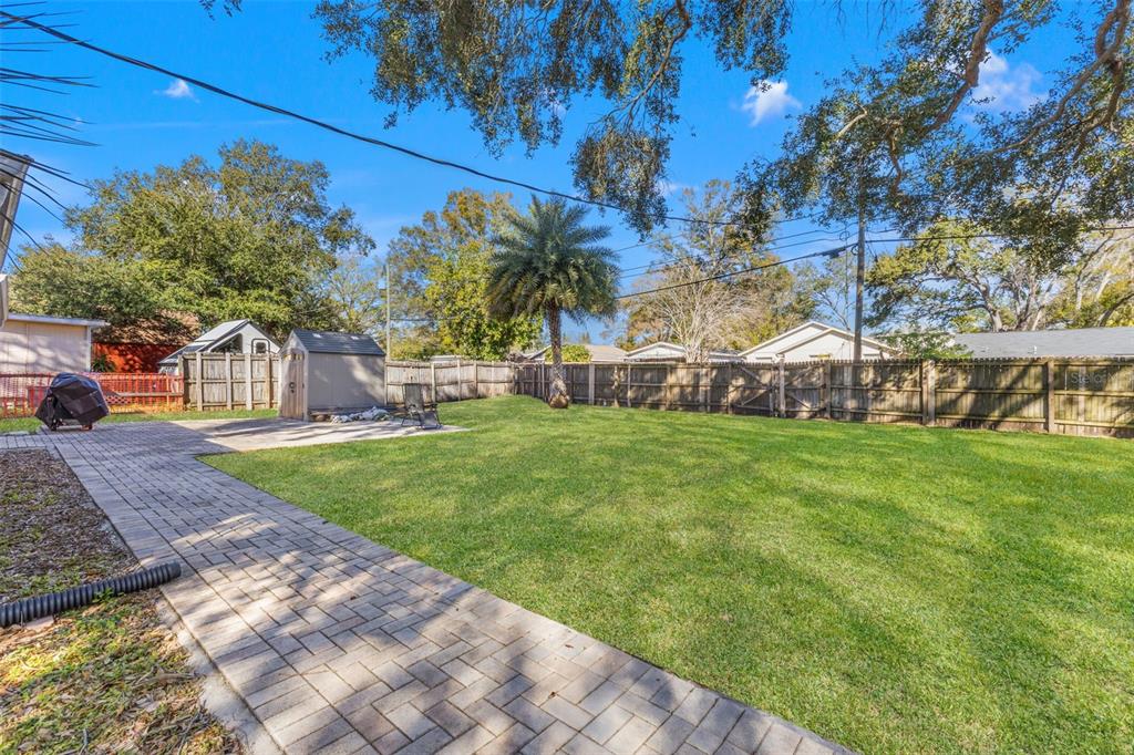 A backyard features a paved patio, a storage shed, a palm tree, and a wooden fence — 1747 26TH AVENUE N, ST PETERSBURG, FL