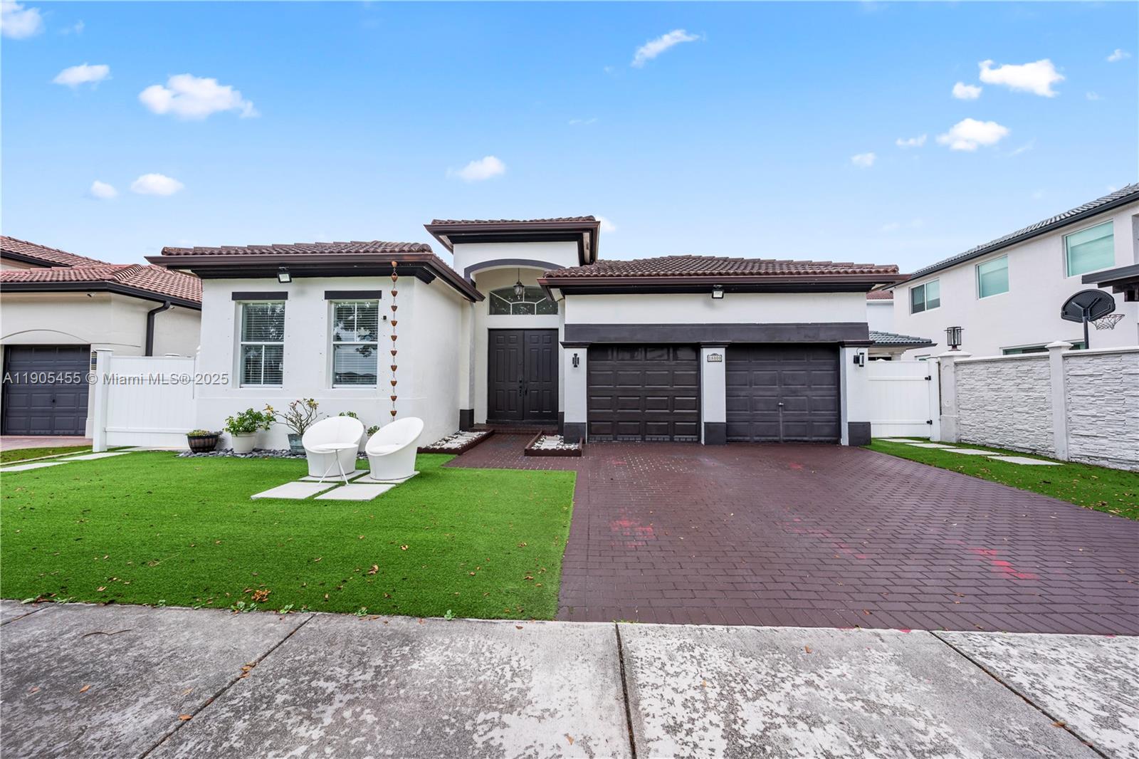 A single-story house with a white exterior, dark garage doors, and a paved driveway — 18000 NW 90th Pl, Hialeah FL 33018, HIALEAH, FL