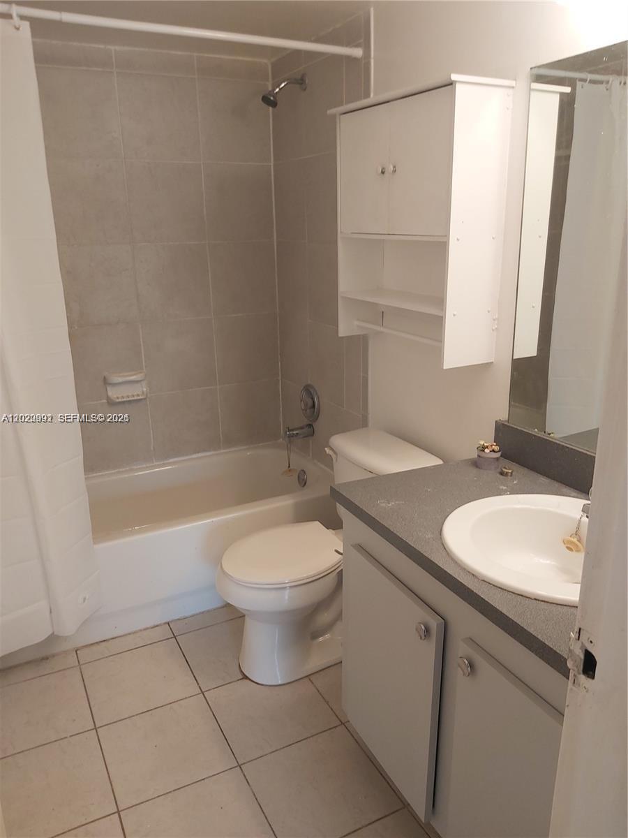 A bathroom features a tiled shower-tub combo, a toilet, and a vanity with a grey countertop — TAMARAC, FL