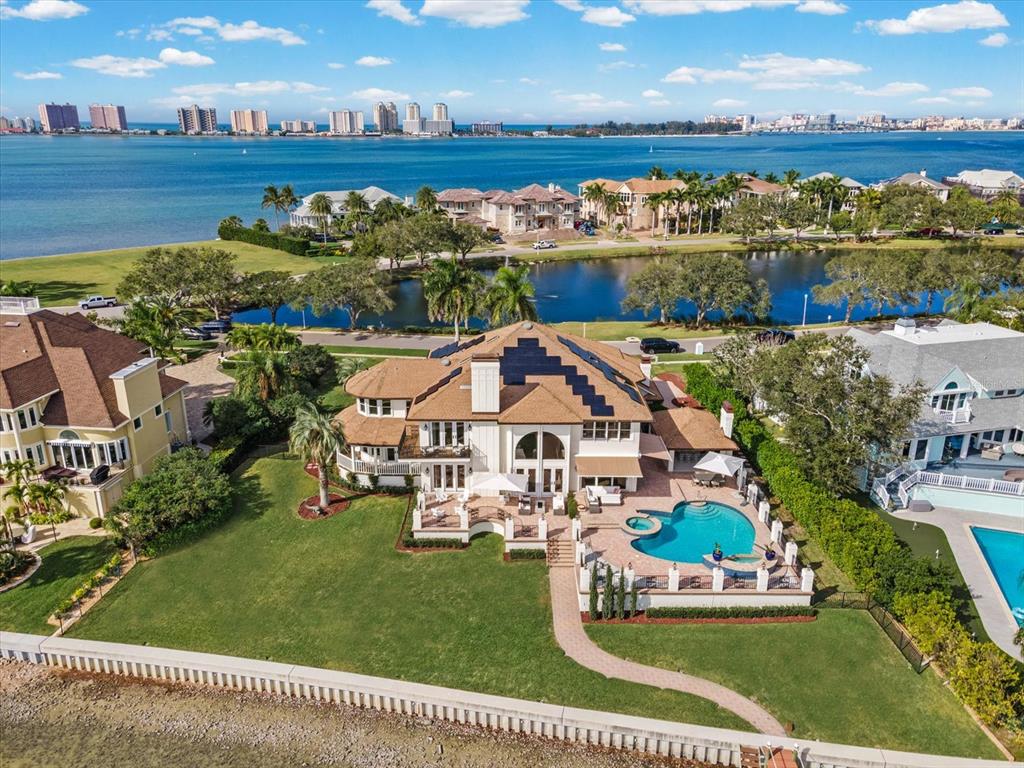 An aerial view of a waterfront house with a pool, lawn, and solar panels — 429 ST ANDREWS DRIVE, BELLEAIR, FL