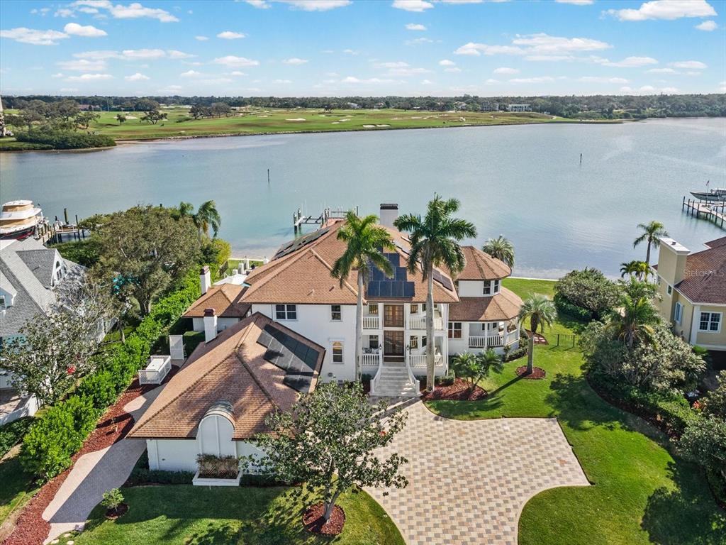 An aerial view of a large waterfront house with a paved driveway and solar panels — 429 ST ANDREWS DRIVE, BELLEAIR, FL
