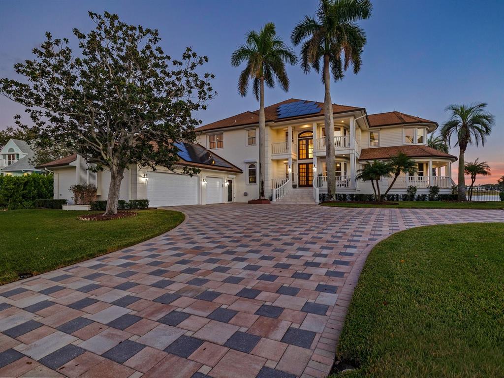 A large two-story house with a paver driveway, palm trees, and solar panels on the roof — 429 ST ANDREWS DRIVE, BELLEAIR, FL