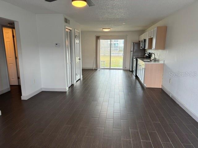 An open-concept living area features dark wood-look tile flooring and a kitchen with light cabinetry — 1883 CARALEE BOULEVARD UNIT 1, ORLANDO, FL