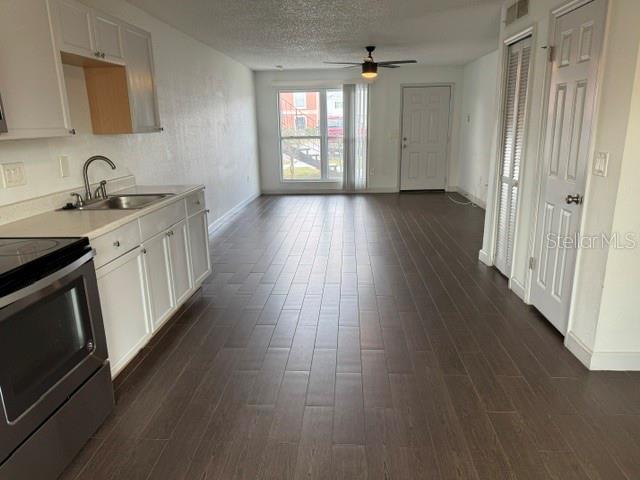 A kitchen with white cabinets and dark wood-look flooring opens into a living area — 1883 CARALEE BOULEVARD UNIT 1, ORLANDO, FL