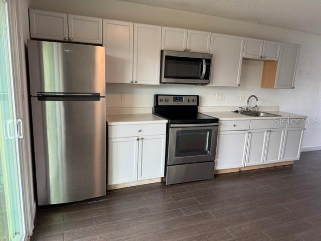 A kitchen with white cabinets, stainless steel appliances, and dark wood-look tile flooring — 1883 CARALEE BOULEVARD UNIT 1, ORLANDO, FL