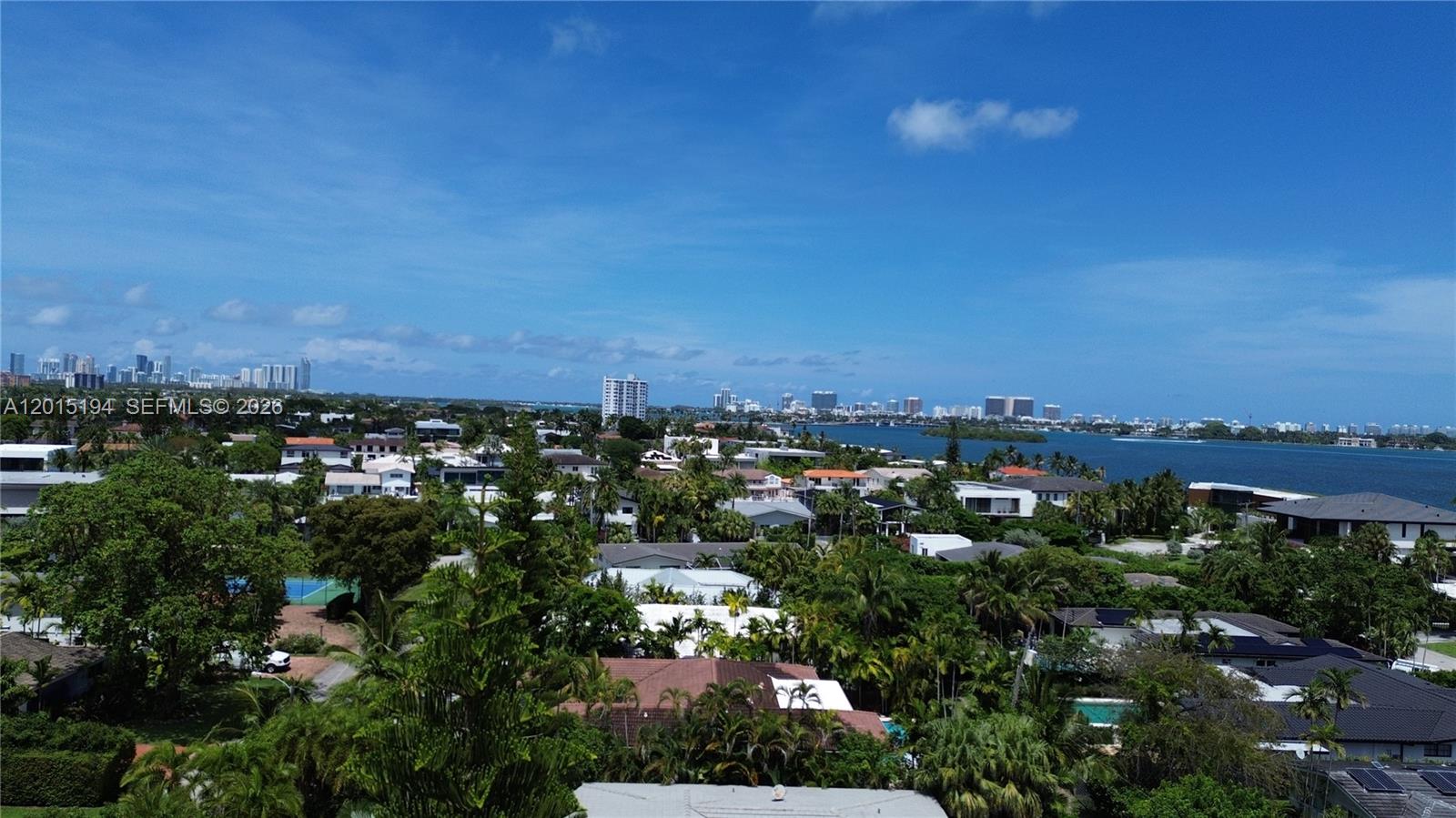 An aerial view shows a coastal residential neighborhood with palm trees and a large bay — 11445 N Bayshore Dr, North Miami FL 33181, NORTH MIAMI, FL