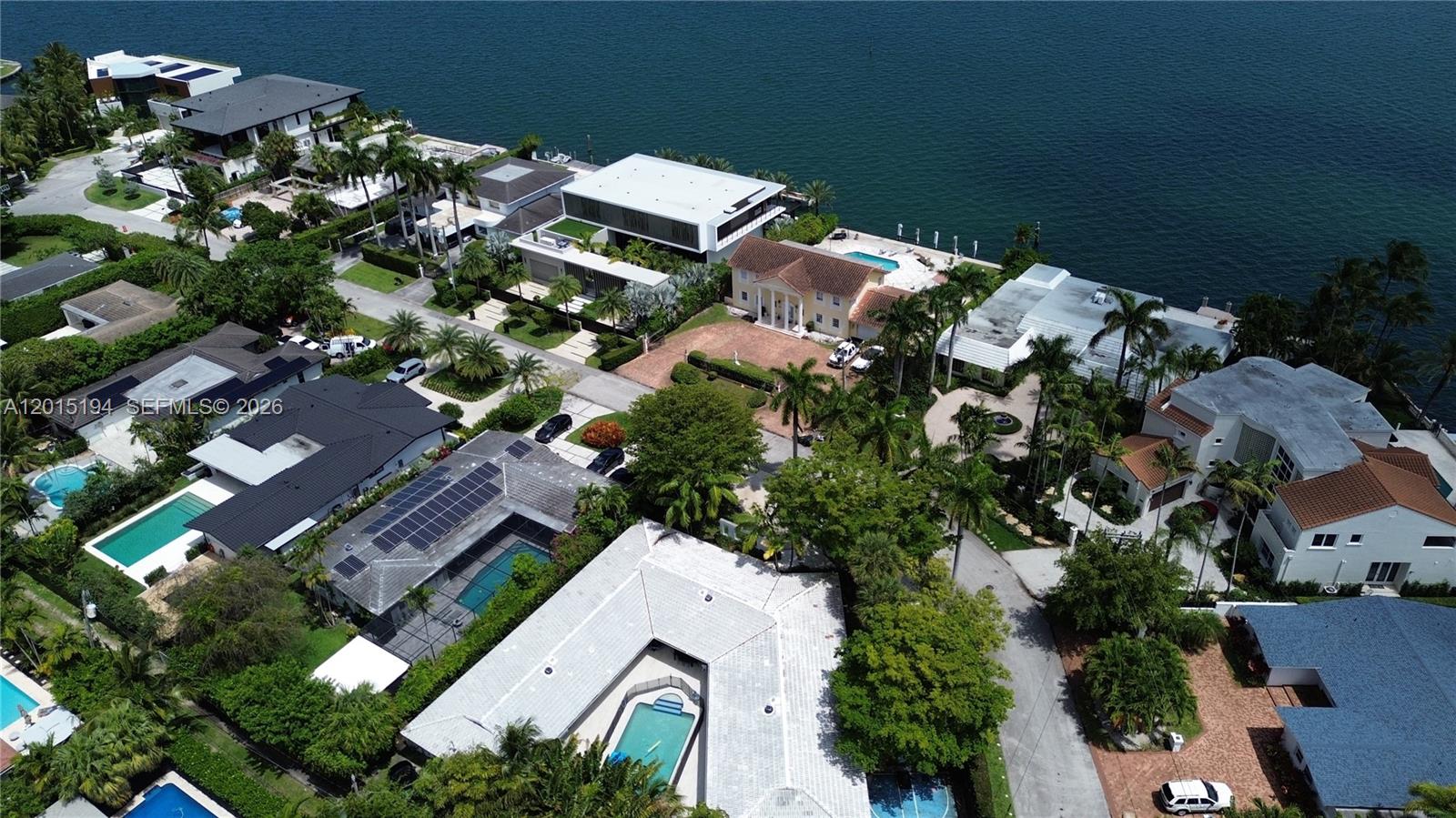An aerial view shows a residential neighborhood with lush trees, houses, and a distant waterway — 11445 N Bayshore Dr, North Miami FL 33181, NORTH MIAMI, FL