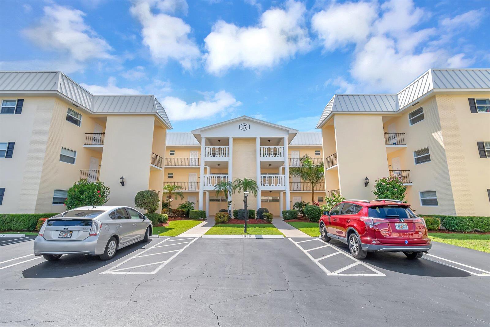 A three-story apartment building with a central entrance and two parked cars in front — 17 Colonial Club Drive # 204, Boynton Beach FL 33435, BOYNTON BEACH, FL