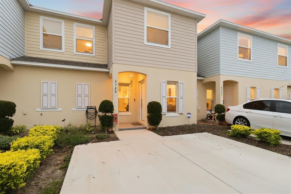 A beige two-story townhouse with a concrete driveway and a small front garden — 4729 CORAL CASTLE DRIVE, KISSIMMEE, FL