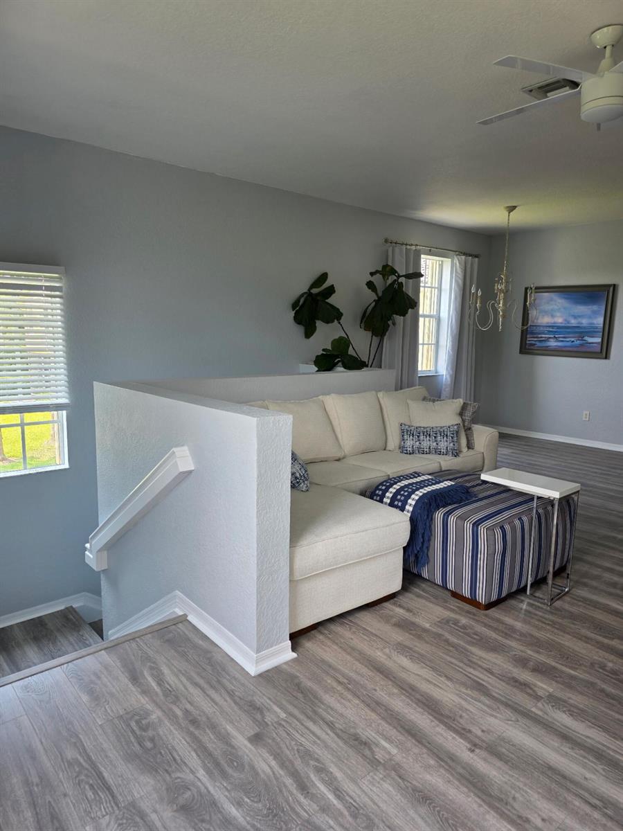 A living room features a sectional sofa, a striped ottoman, and light wood-look flooring — 1560 SE Hampshire Way # 204, Stuart FL 34994, STUART, FL