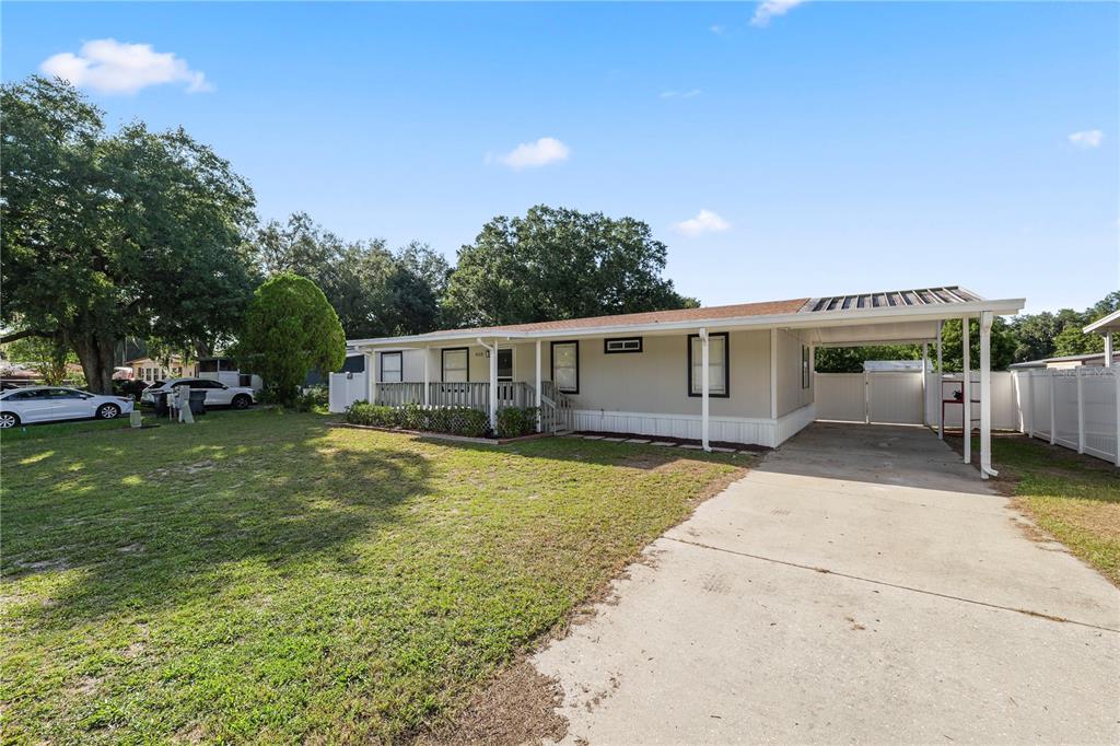 A single-story manufactured home with a front porch, attached carport, and a concrete driveway — 3113 ROLLINGLEN LANE, LAKELAND, FL
