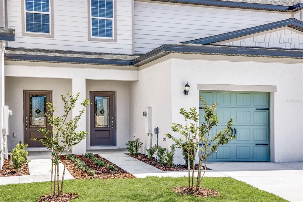A two-story townhouse exterior features a light blue garage door and two brown entry doors — 697 POPPY LANE, DUNDEE, FL
