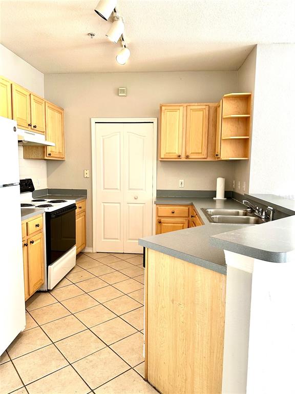 A kitchen with light wood cabinets, gray countertops, tile flooring, and a white refrigerator — 1150 LAKE SHADOW CIRCLE UNIT 3102, MAITLAND, FL