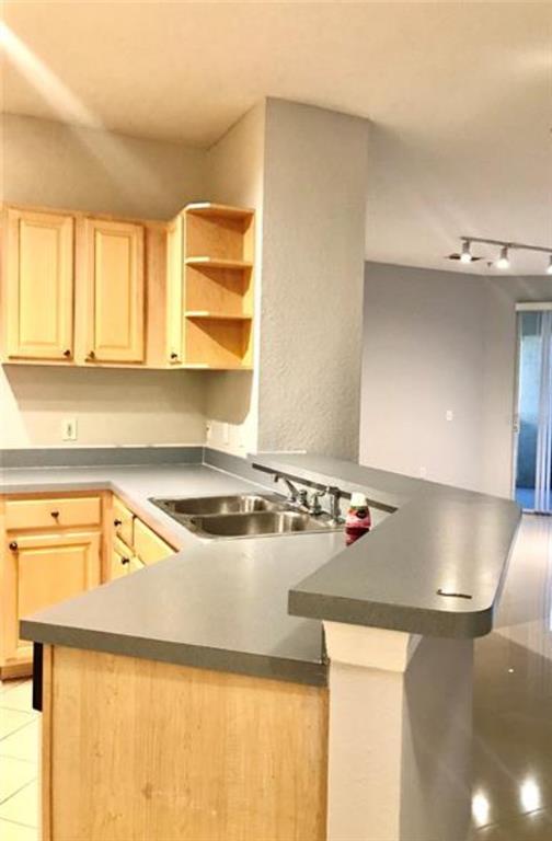 A kitchen features light wood cabinets, gray countertops, and a breakfast bar overlooking a room — 1150 LAKE SHADOW CIRCLE UNIT 3102, MAITLAND, FL