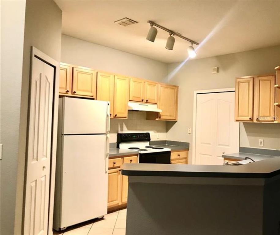 A kitchen with light wood cabinets, white appliances, and a gray countertop peninsula — 1150 LAKE SHADOW CIRCLE UNIT 3102, MAITLAND, FL