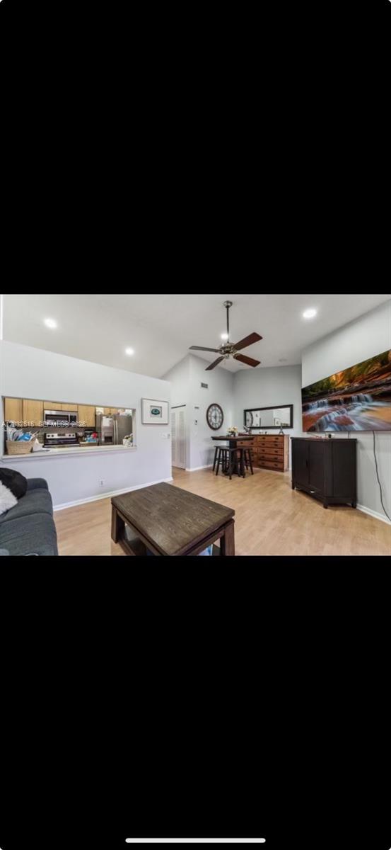 A living room with light wood flooring, a ceiling fan, and an open kitchen pass-through — 306 Republic Ct # 306, Deerfield Beach FL 33442, DEERFIELD BEACH, FL