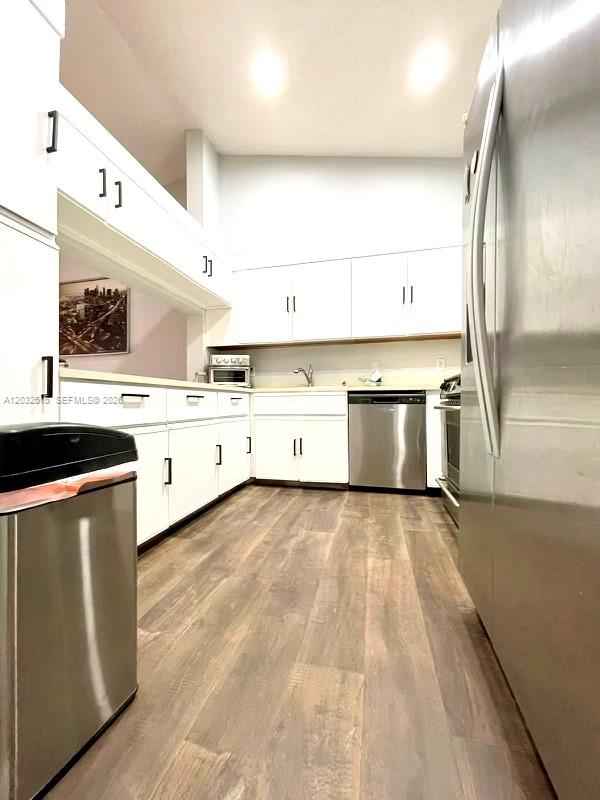 A galley kitchen features white cabinets, stainless steel appliances, and wood-look flooring — 306 Republic Ct # 306, Deerfield Beach FL 33442, DEERFIELD BEACH, FL