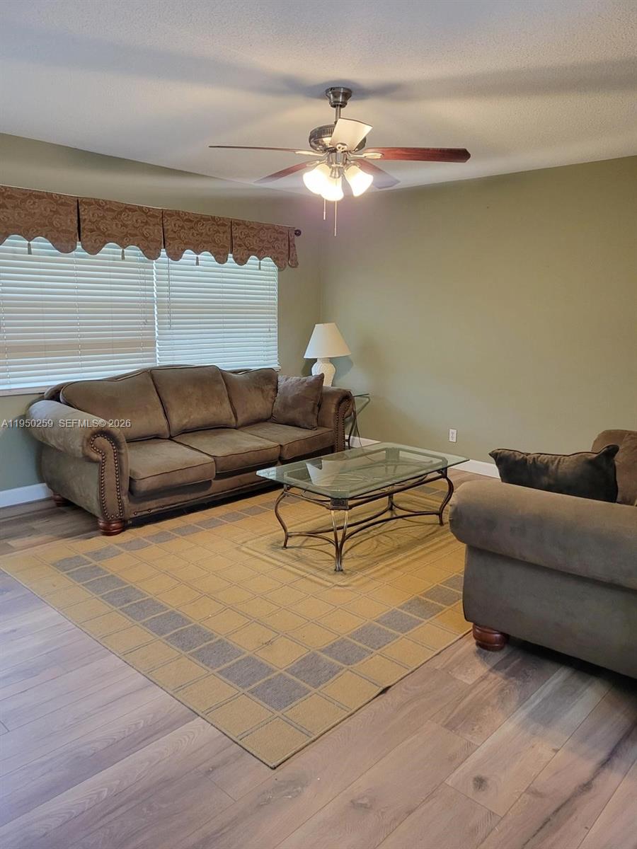 A living room features a brown sofa, a glass coffee table, and a ceiling fan — 2031 Dewey St # 302, Hollywood FL 33020, HOLLYWOOD, FL