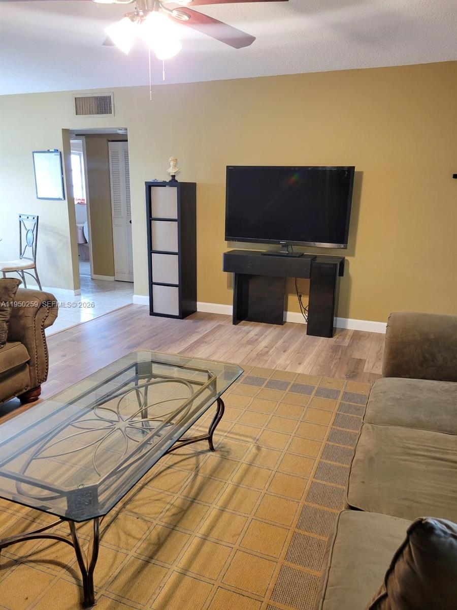 A living room features a television on a console, a shelving unit, and a glass-topped table — 2031 Dewey St # 302, Hollywood FL 33020, HOLLYWOOD, FL