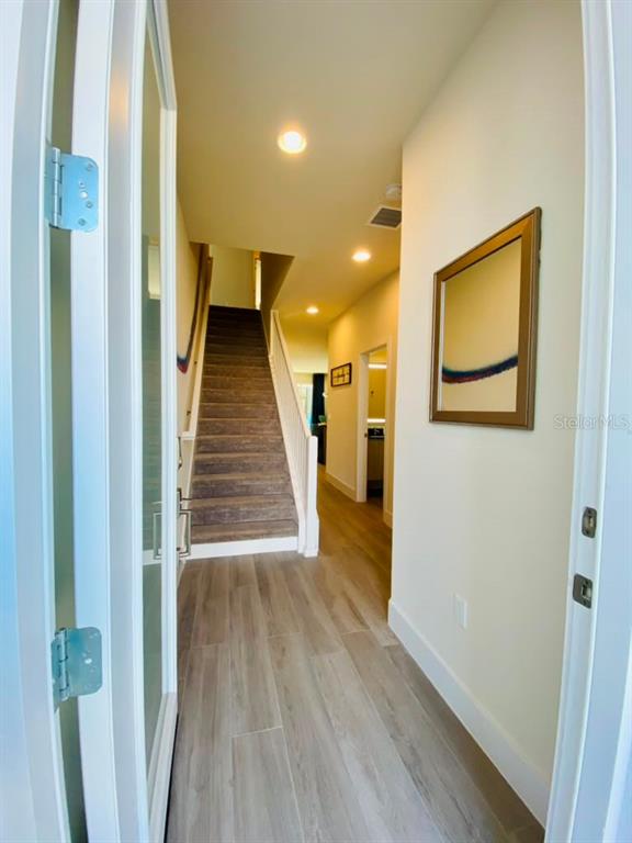 An entryway features light wood-look flooring, a carpeted staircase, and a framed wall art piece — 17214 BLESSING DRIVE, CLERMONT, FL