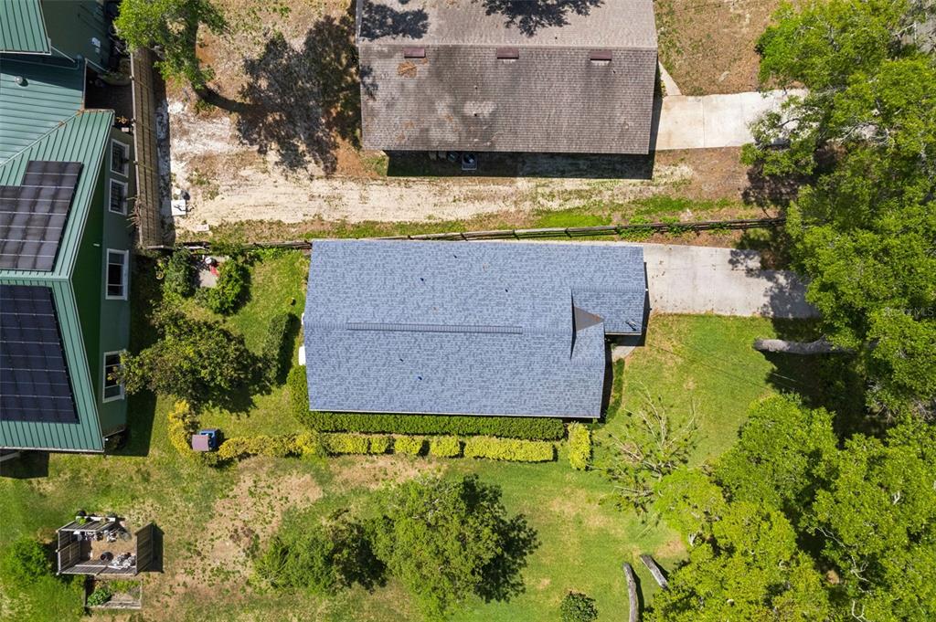 An aerial view shows a house with a gray roof next to a green-roofed building — 30904 DEAL DRIVE, SORRENTO, FL