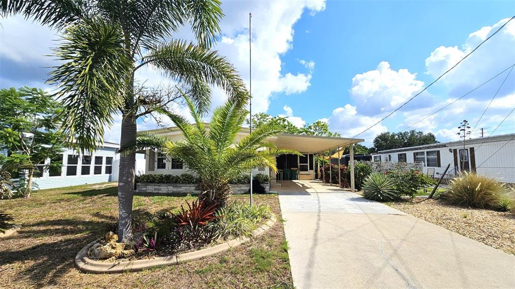 A mobile home with a carport, a concrete driveway, and palm trees in the front yard — 1240 SEAGULL DRIVE, ENGLEWOOD, FL