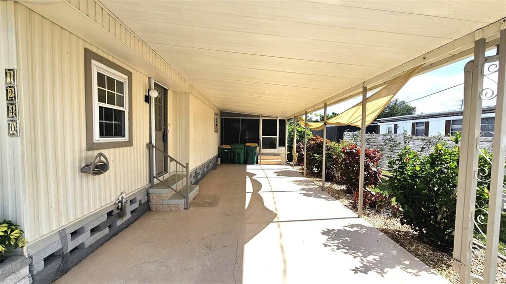 A covered concrete carport runs alongside the exterior wall of a mobile home — 1240 SEAGULL DRIVE, ENGLEWOOD, FL