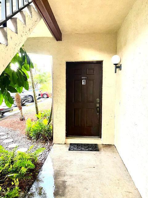 A brown front door with the number one is located under a covered entryway — 3303 Kirk Road # 1, Lake Worth FL 33461, LAKE WORTH, FL