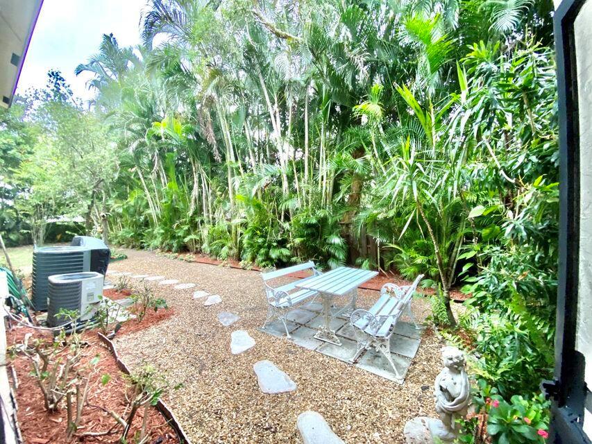 A gravel backyard features a white metal bistro set, stepping stones, and lush tropical landscaping — 3303 Kirk Road # 1, Lake Worth FL 33461, LAKE WORTH, FL