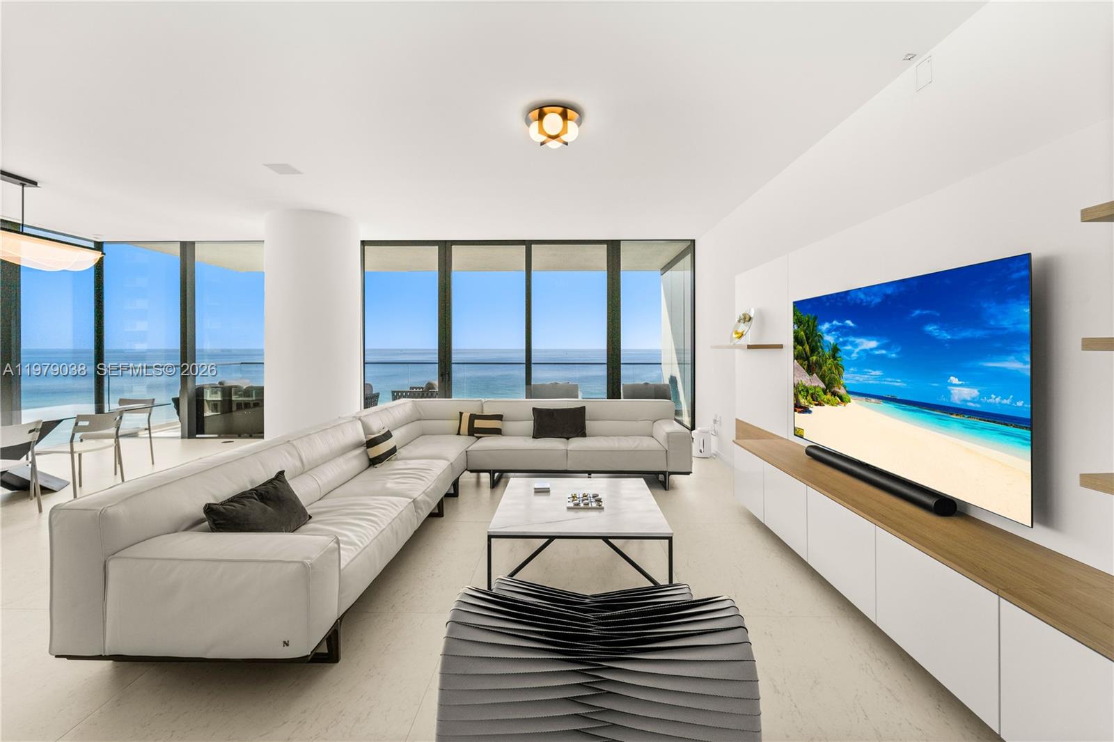 A modern living room features a white sectional sofa, a television, and floor-to-ceiling ocean views — 2000 S Ocean Dr # 8A, Hallandale Beach FL 33009, HALLANDALE BEACH, FL