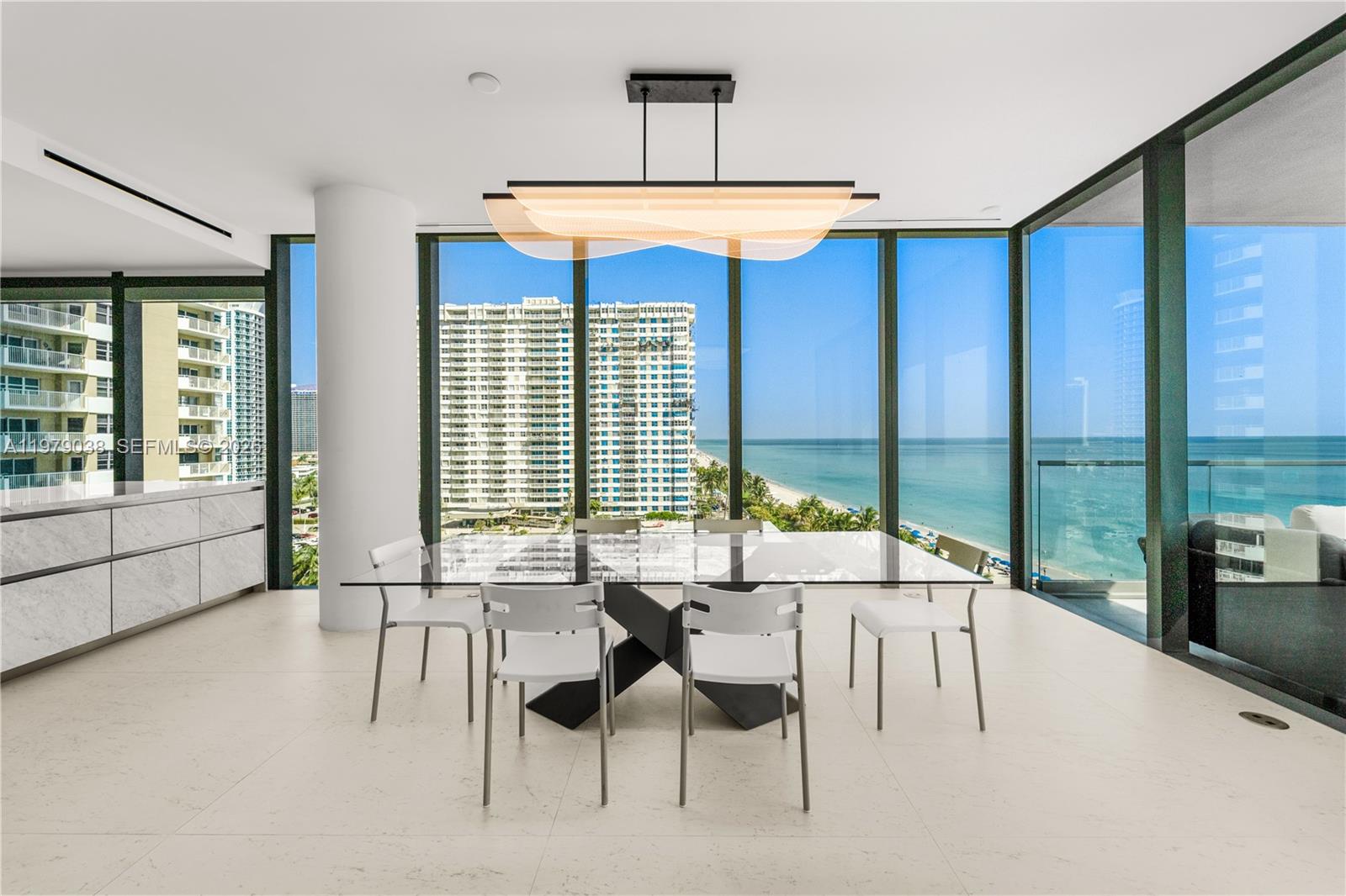 A modern dining room features a glass table, white chairs, and floor-to-ceiling ocean views — 2000 S Ocean Dr # 8A, Hallandale Beach FL 33009, HALLANDALE BEACH, FL