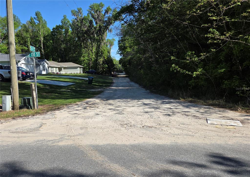 A dirt road leads into a wooded area next to a residential house and street sign — 0000 SE 42ND COURT, BELLEVIEW, FL