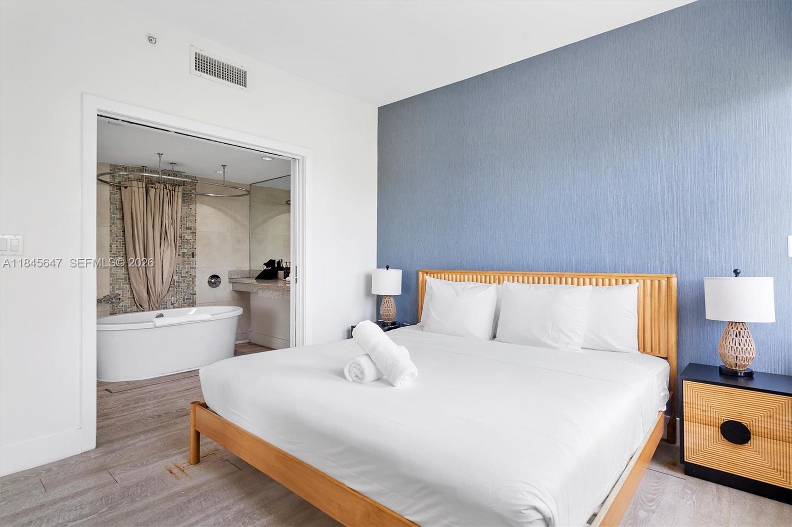 A bedroom with a blue accent wall features a bed and an attached bathroom — 1060 Ocean Dr # D303, Miami Beach FL 33139, MIAMI BEACH, FL