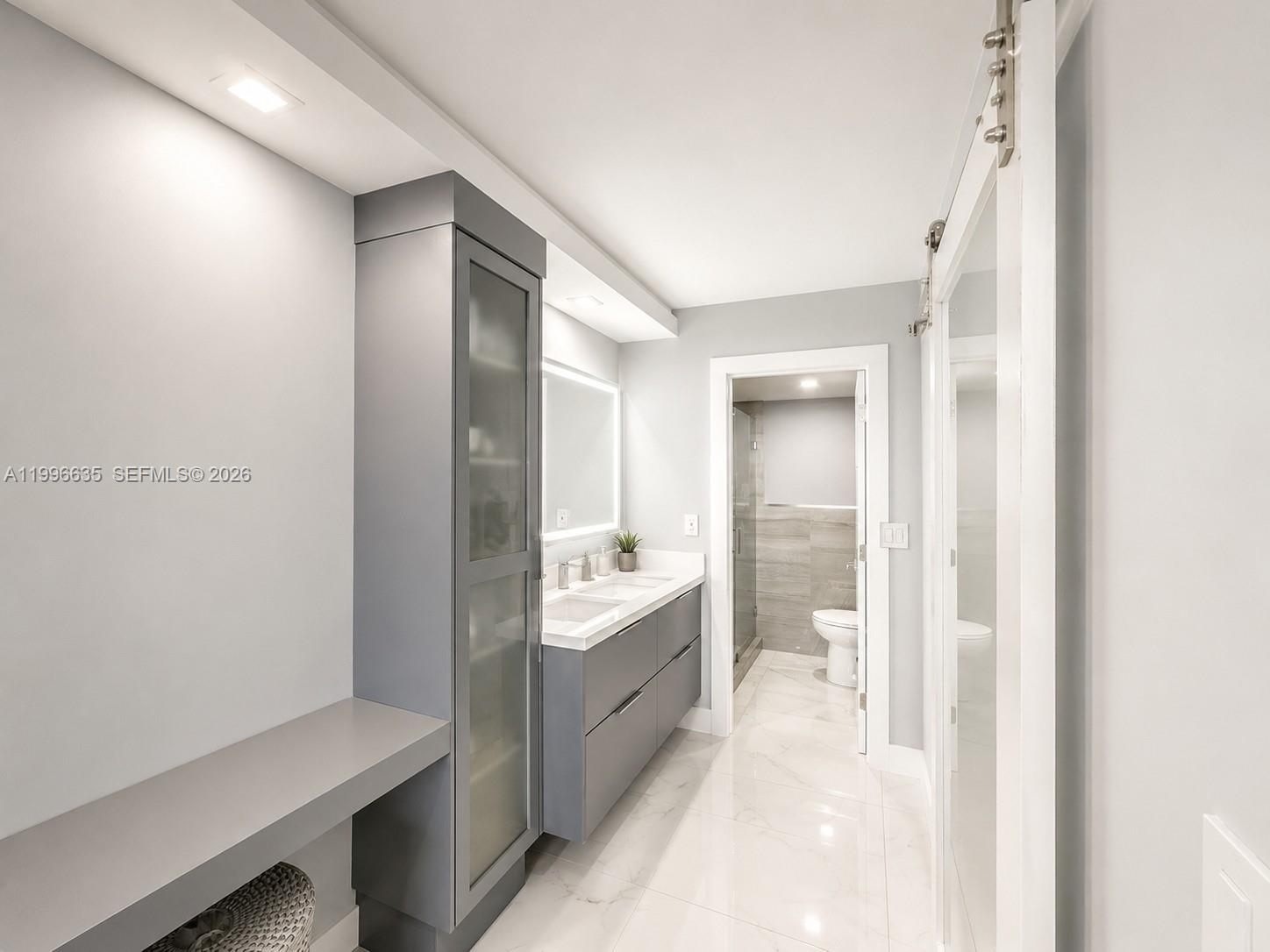 A modern bathroom features a gray vanity, a tall storage cabinet, and marble-look tile flooring — 1420 Brickell Bay Dr # 702E, Miami FL 33131, MIAMI, FL