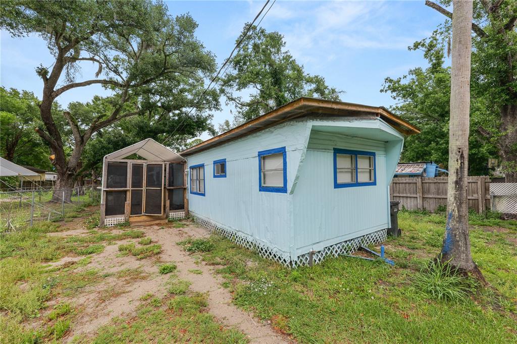 A light blue mobile home with a screened-in porch sits on a grassy lot — 829 NASHVILLE ROAD, LAKELAND, FL