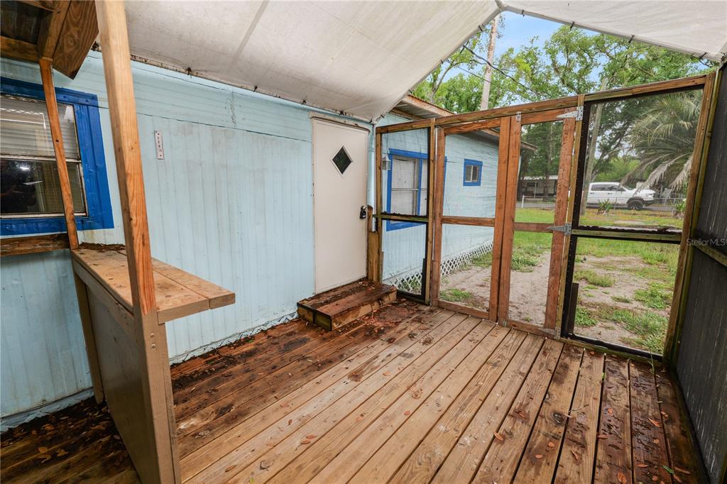 A wooden deck with a covered screen enclosure attached to a light blue mobile home — 829 NASHVILLE ROAD, LAKELAND, FL