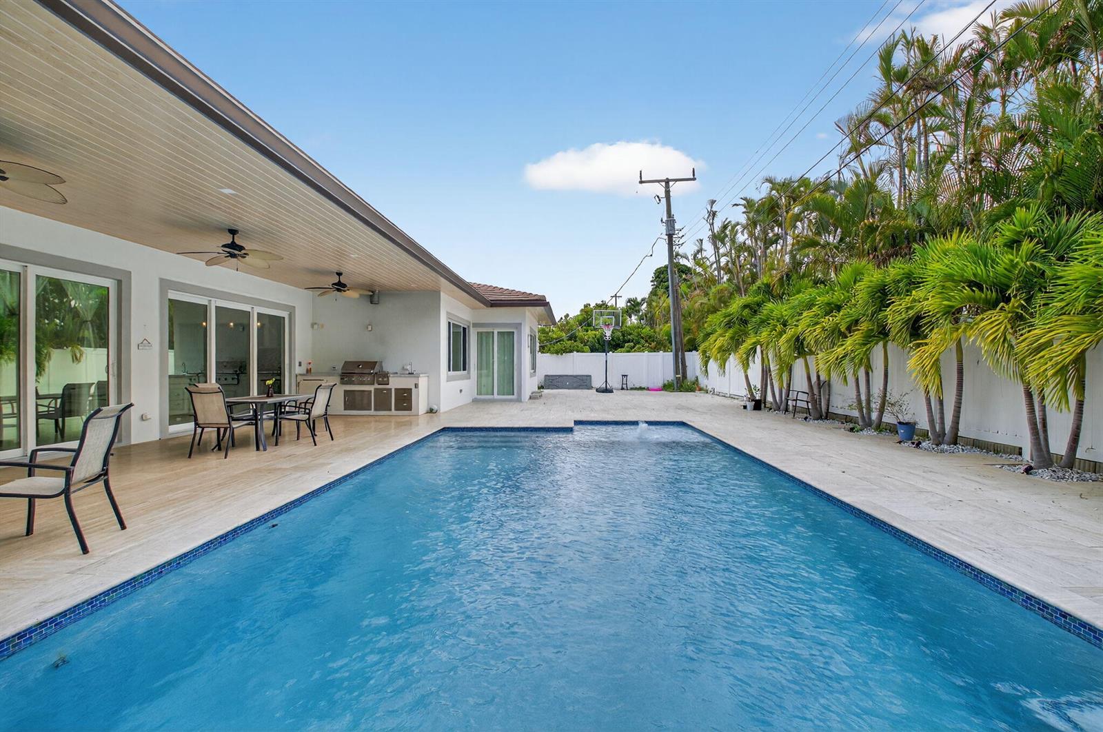 A rectangular swimming pool sits on a patio next to a house with a covered porch — 711 NE 6th Street, Boca Raton FL 33432, BOCA RATON, FL