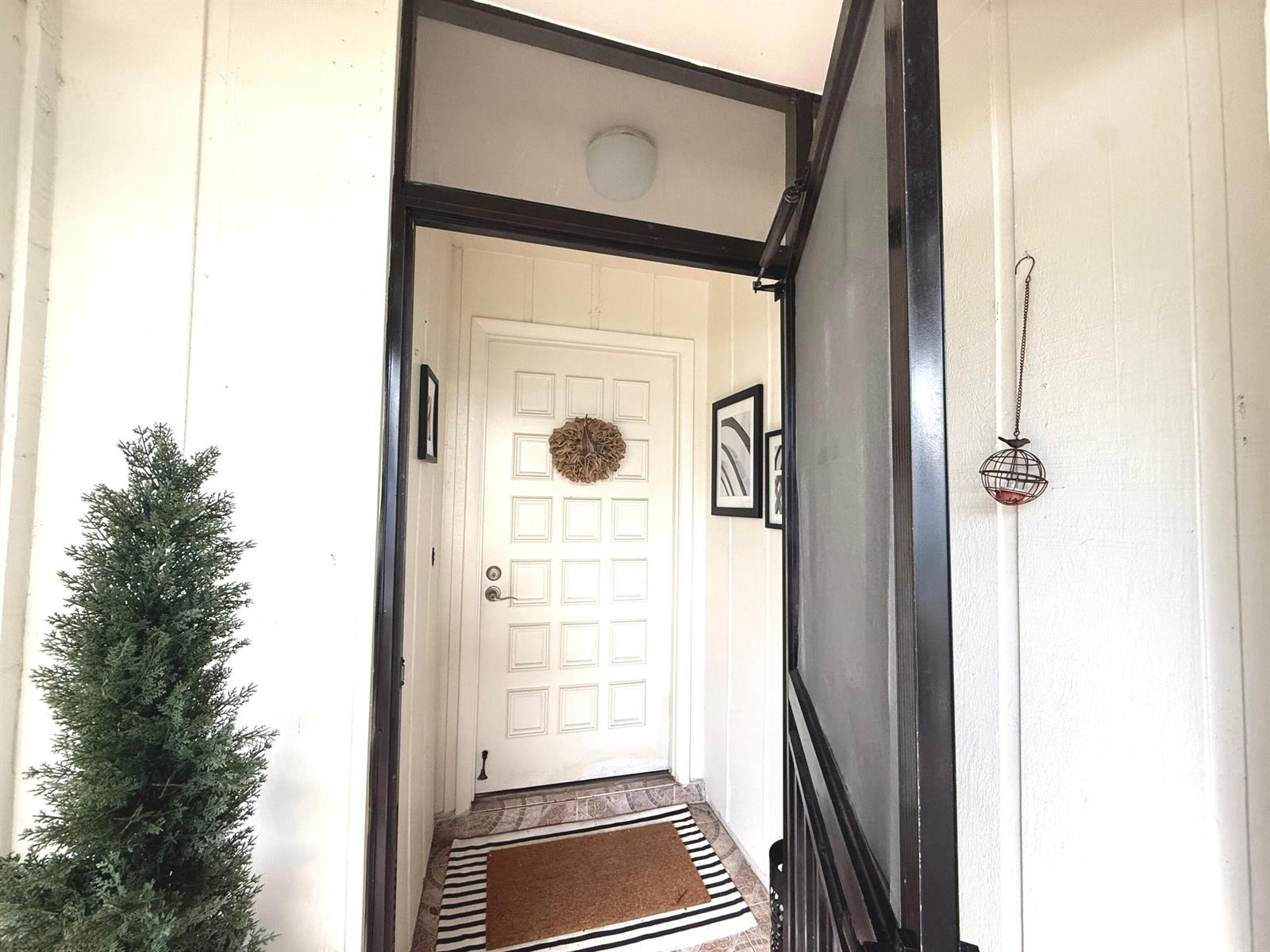 An open black screen door leads to a white front door with a wreath — 15860 Laurel Oak Circle, Delray Beach FL 33484, DELRAY BEACH, FL