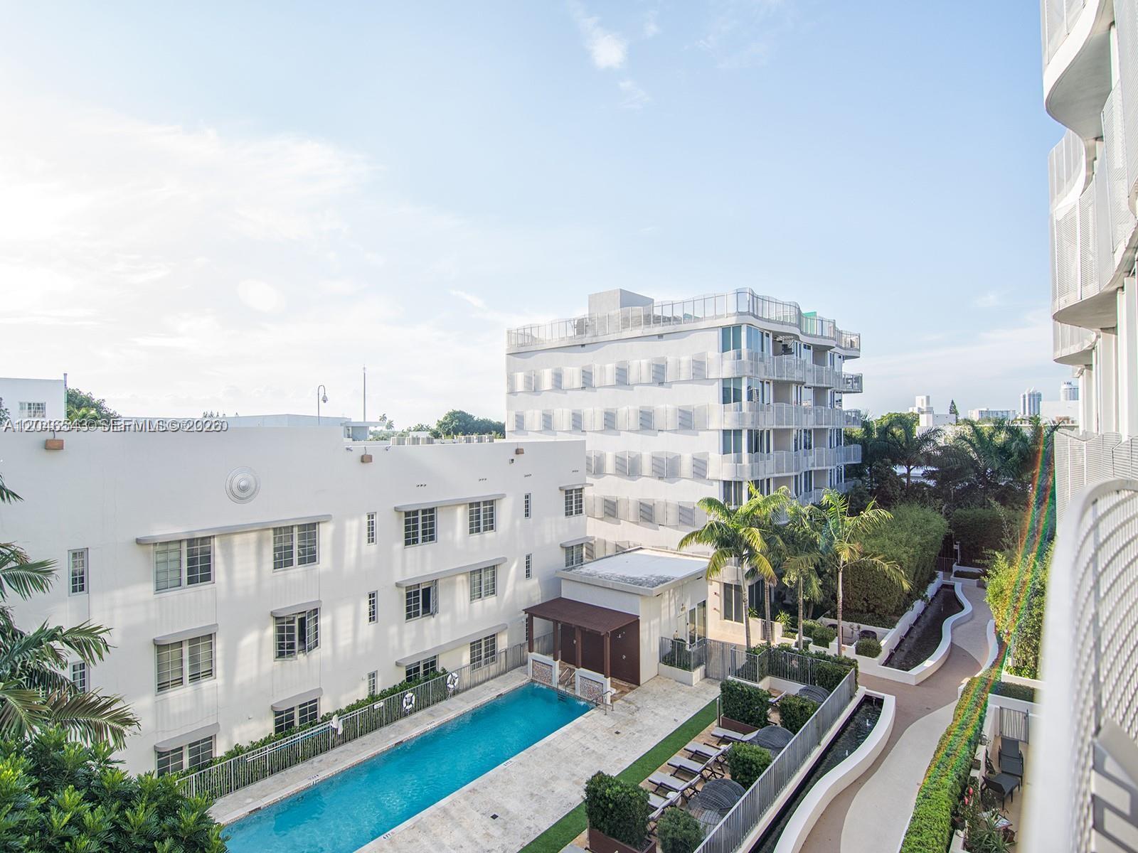 An elevated view shows a swimming pool area between two multi-story apartment buildings — 2100 Park Ave # 406, Miami Beach FL 33139, MIAMI BEACH, FL