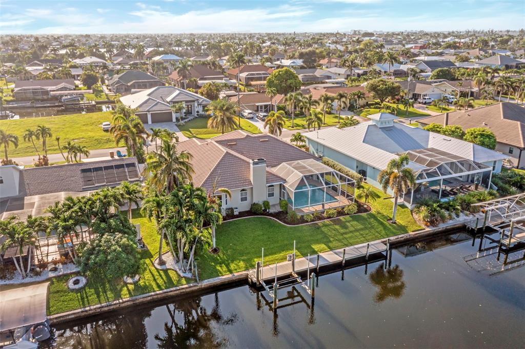 An aerial view of a waterfront house with a pool, screened lanai, and private dock — 5212 SW 8TH COURT, CAPE CORAL, FL