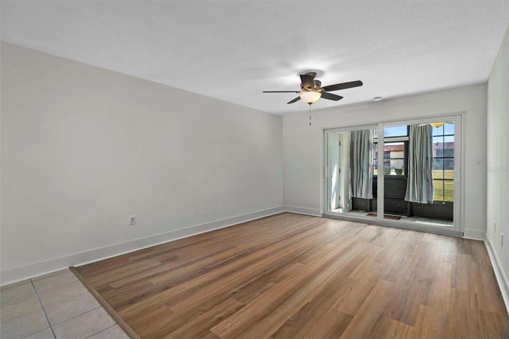 An empty room with wood-look flooring, a ceiling fan, and sliding glass doors to a patio — 5154 TURQUOISE LANE UNIT 106, NEW PORT RICHEY, FL