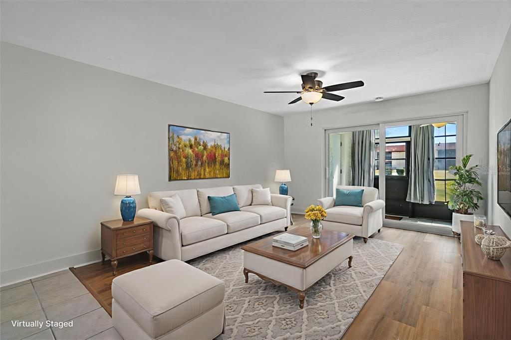 A living room features a beige sofa, armchair, coffee table, and sliding glass patio doors — 5154 TURQUOISE LANE UNIT 106, NEW PORT RICHEY, FL