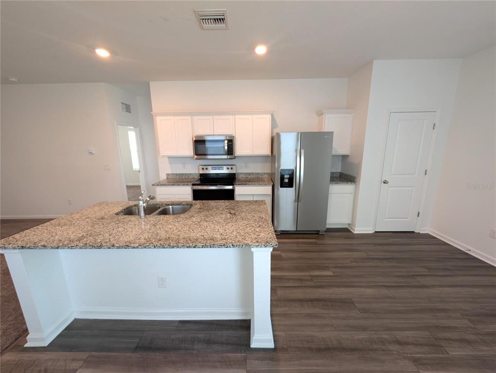 A kitchen features white cabinets, granite countertops, stainless steel appliances, and a central island — 35491 SHADE FERN LANE, ZEPHYRHILLS, FL