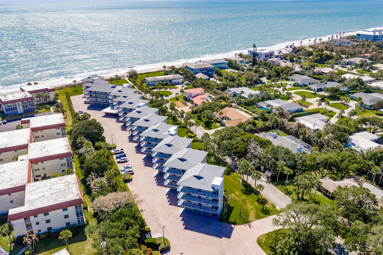 An aerial view shows a multi-story residential complex situated along a sandy beach — INDIAN RIVER SHORES, FL