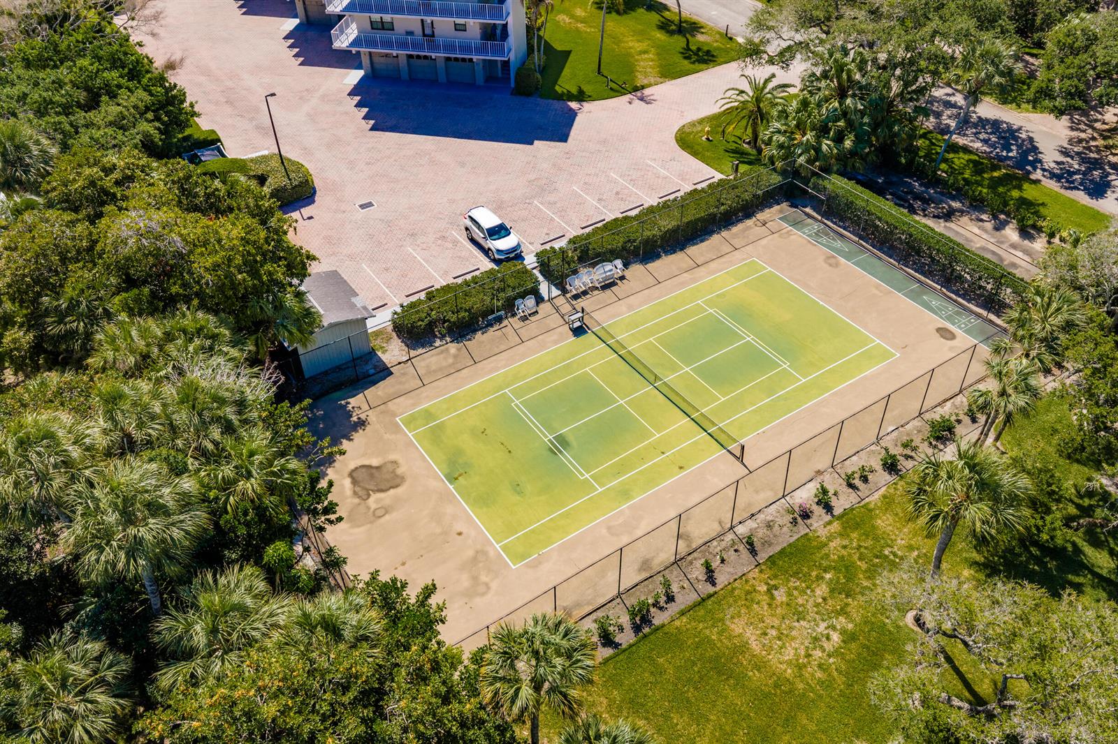 An aerial view shows a tennis court next to a parking lot and a building — INDIAN RIVER SHORES, FL