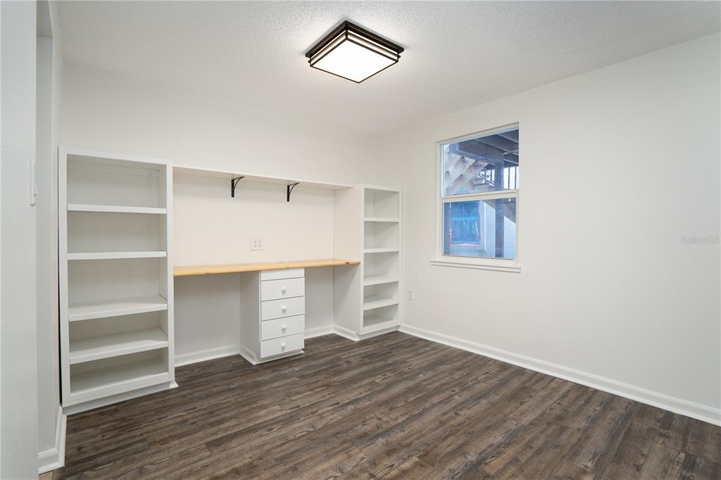 A home office features built-in shelving, a desk with drawers, and dark wood-look flooring — 22291 WESTCHESTER BOULEVARD UNIT 301, PORT CHARLOTTE, FL