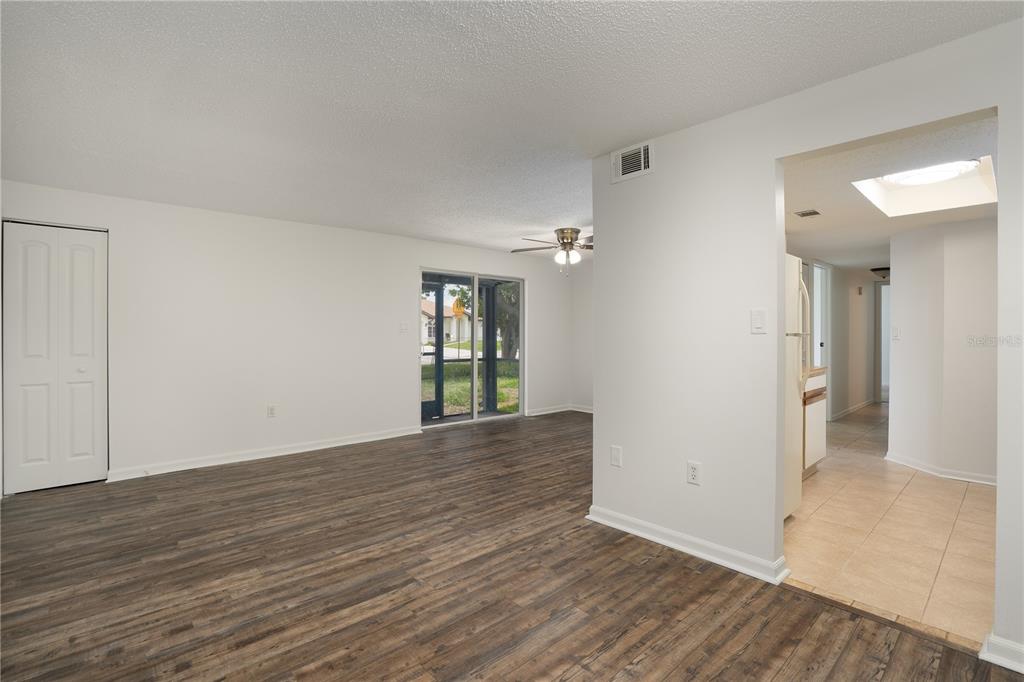 An open living area with wood-look flooring leads to a tiled kitchen and sliding glass doors — 22291 WESTCHESTER BOULEVARD UNIT 301, PORT CHARLOTTE, FL