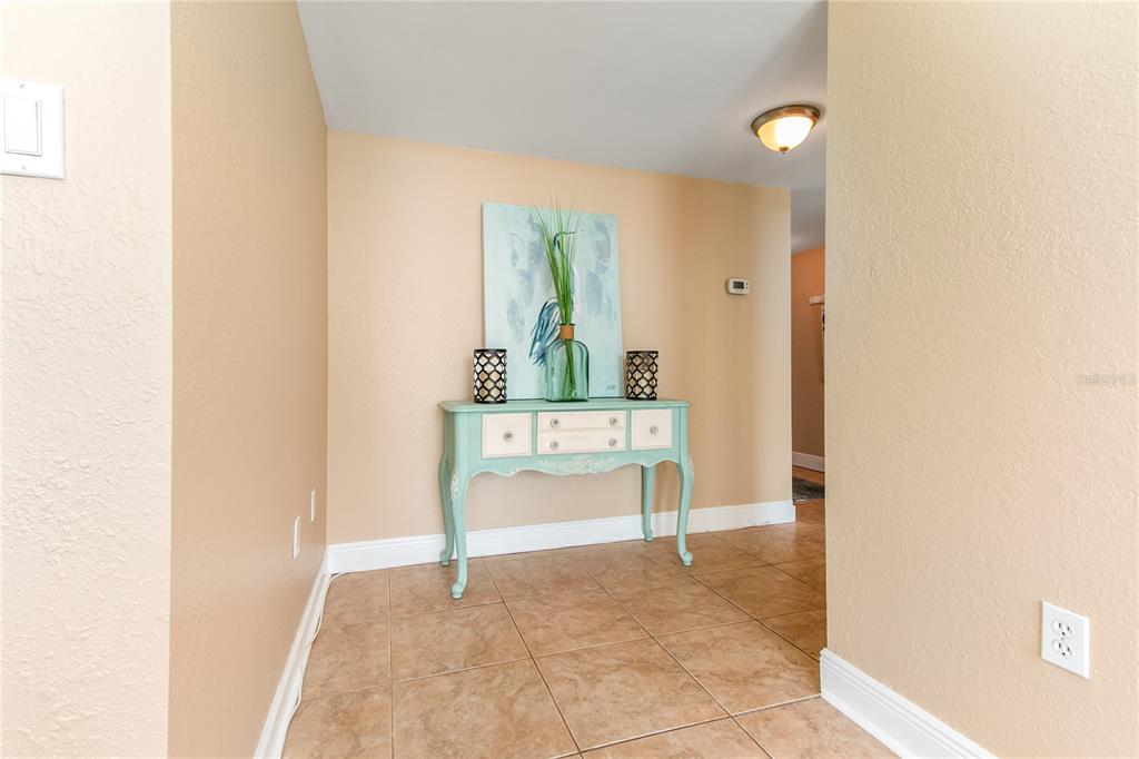 A light blue console table sits against a beige wall in a tiled entryway — 400 ISLAND WAY UNIT 212, CLEARWATER BEACH, FL